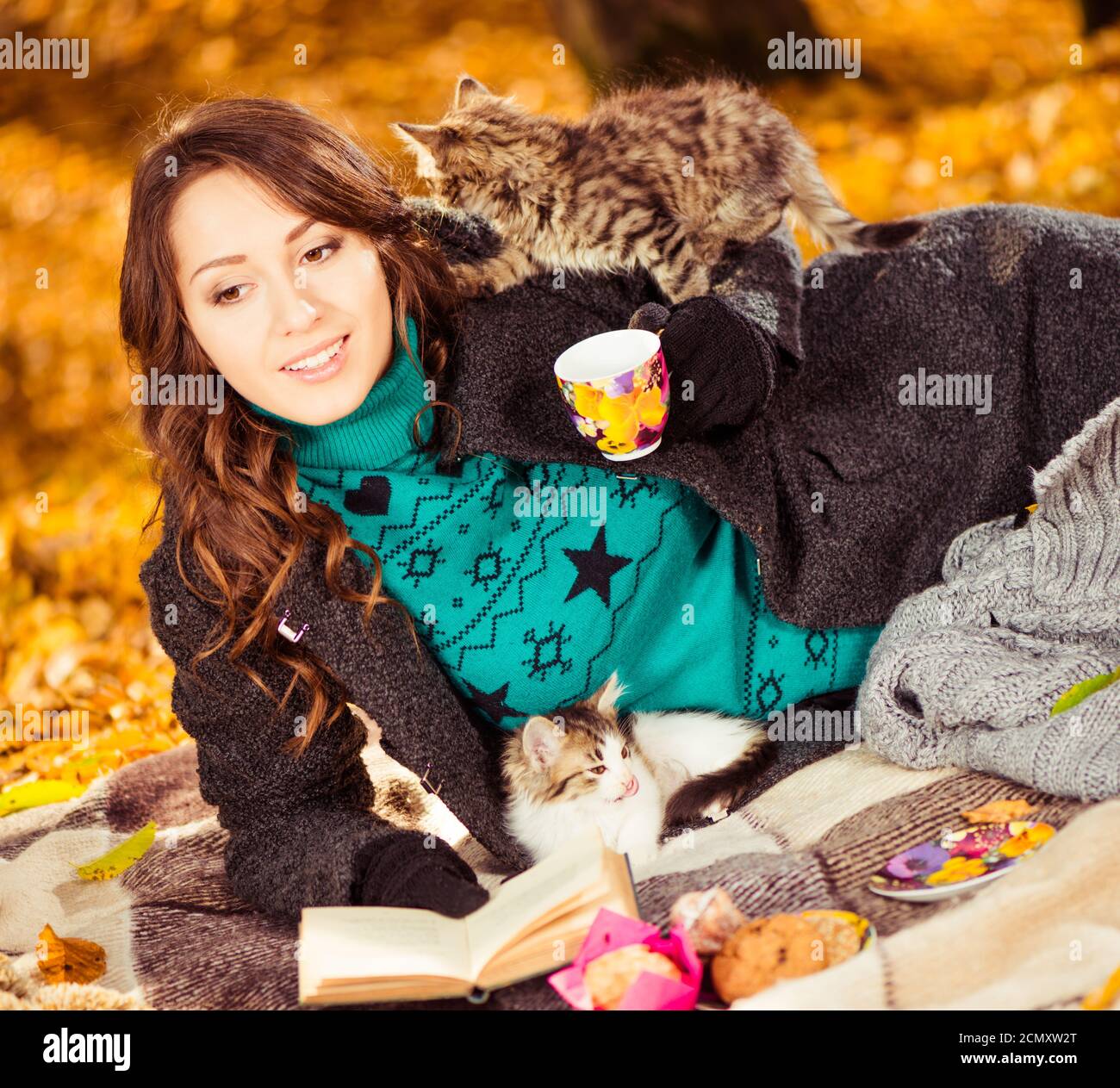 dame mit Buch und zwei kleine verspielte Katzen im Herbst Wald Stockfoto
