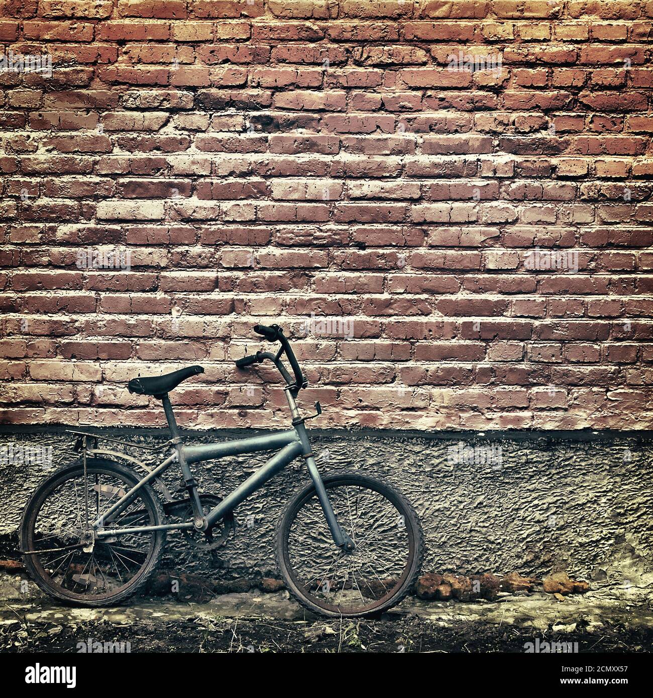 Alte rostige Oldtimer Fahrrad gegen eine Mauer gelehnt Stockfoto