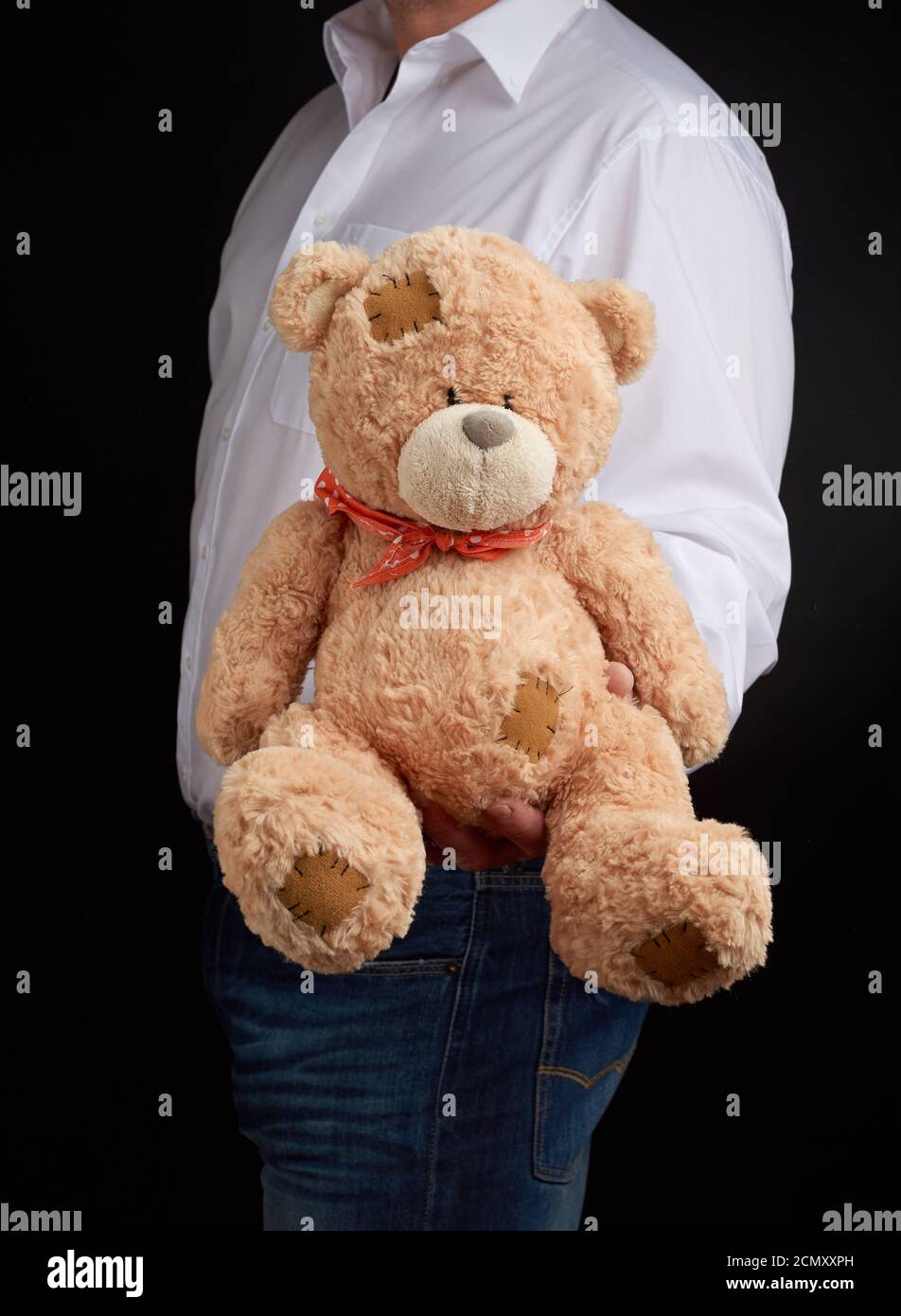 Mann in einem weißen Hemd hält einen großen Teddy beige Tragen Sie mit Flecken Stockfoto