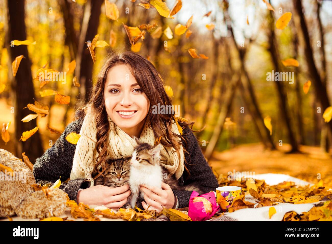 dame mit Buch und zwei kleine verspielte Katzen im Herbst Wald Stockfoto