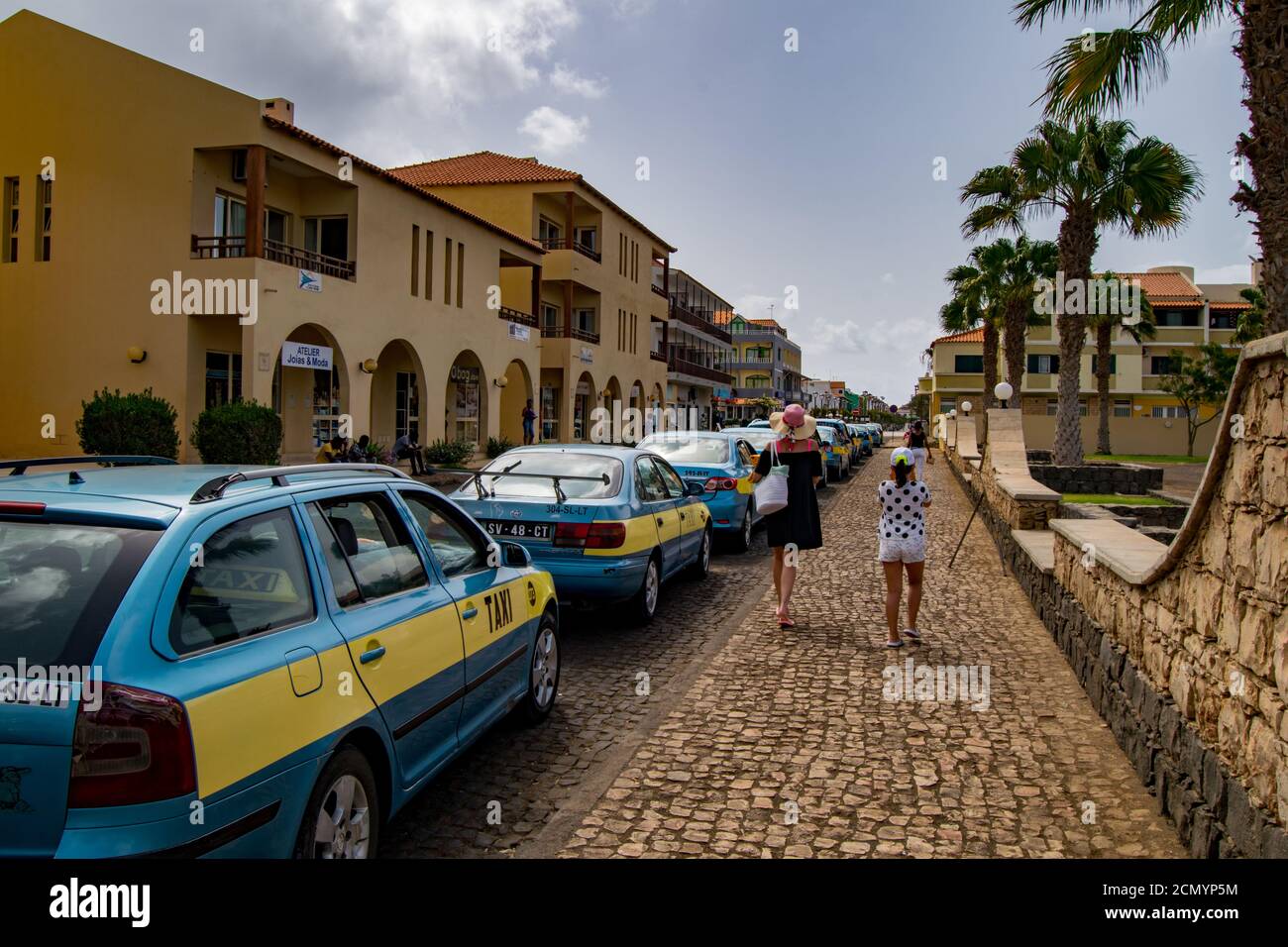 Taxi Taxi Farben blau und gelb in Cabo Verde Insel Salz, ilha do Sal, alleinerziehende Mutter, Mutter und Tochter vorbei oder zu Fuß auf dem Gehwege Stockfoto