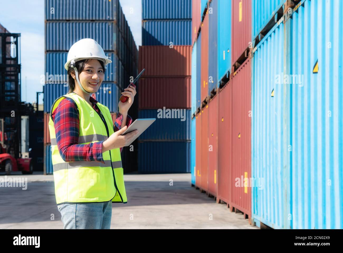 Ingenieurin oder Vorarbeiter im Container-Depot, mit dem gearbeitet wird Digitales Tablet und Walkie Talkie für die Steuerung und Kontrolle Industrie Containerhof Stockfoto