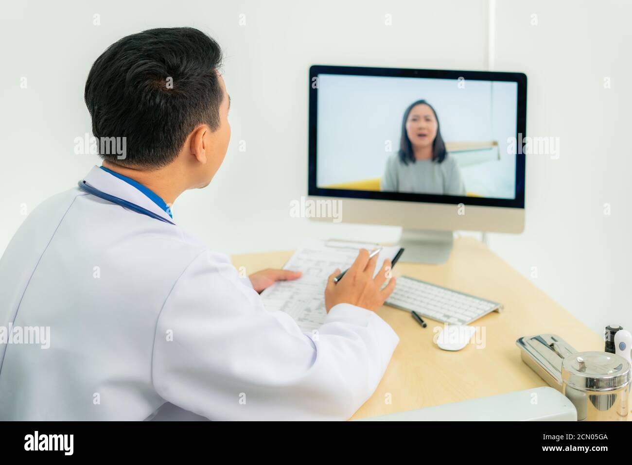 Asiatischer Mann Arzt trägt weißen Mantel und Headset sprechen Videokonferenzen auf Laptop-Computer mit Online-Videoanruf Beratung App. Medizinische Fernversorgung Stockfoto