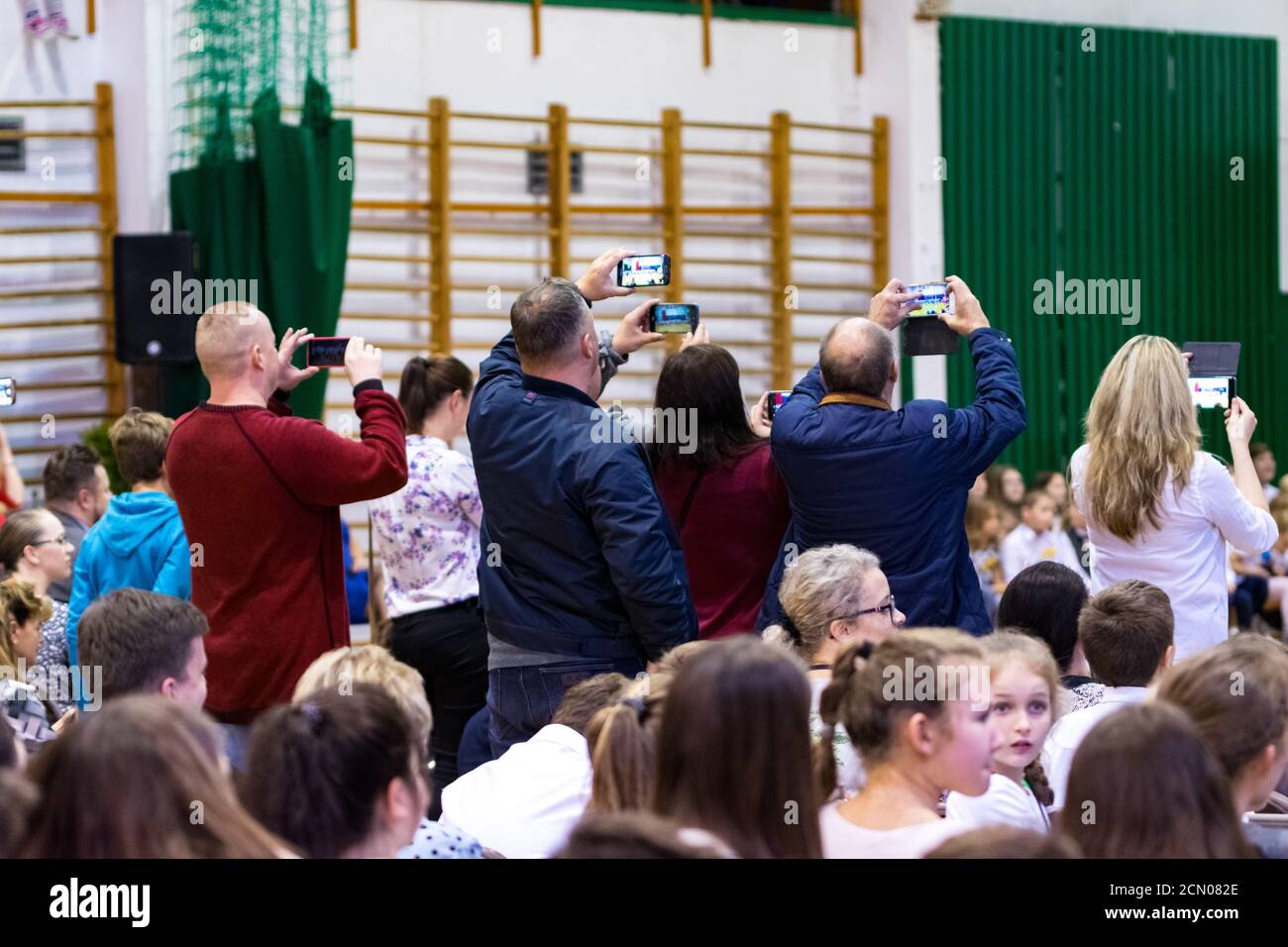 Legionowo, Polen - 25. Oktober 2019: Beginn des Schuljahres. Schüler, Eltern und Lehrer in der Turnhalle während der Schulfeier. Kinder in Form Stockfoto