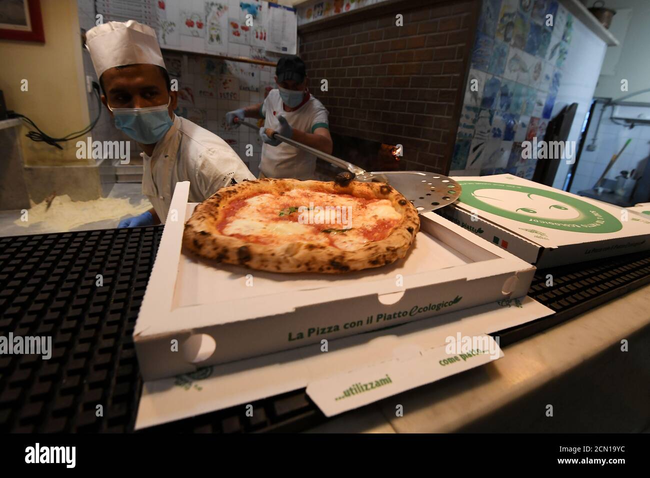 Mitarbeiter in der Peppo al Cosimato Pizzeria, die Gesichtsschutzmasken und  Handschuhe tragen, stellen nach dem Ausbruch der Coronavirus-Krankheit  (COVID-19) in Rom, Italien, am 24. April 2020 Pizzen zur Lieferung bereit.  REUTERS/Alberto Lingria