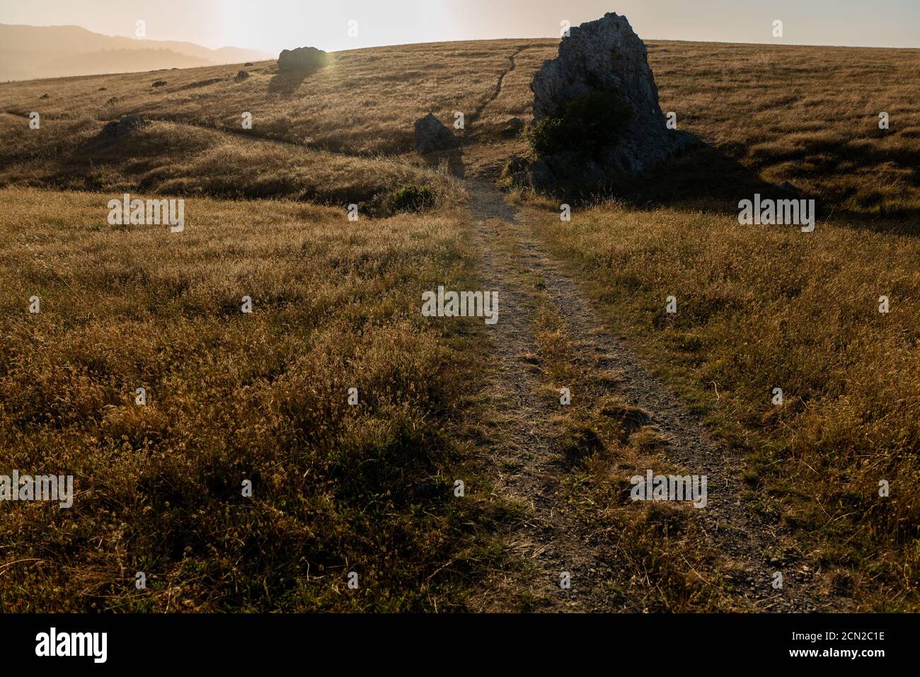 Coastal Trail in der Ferne gesehen über braunen Hügeln während des Sonnenuntergangs Stockfoto