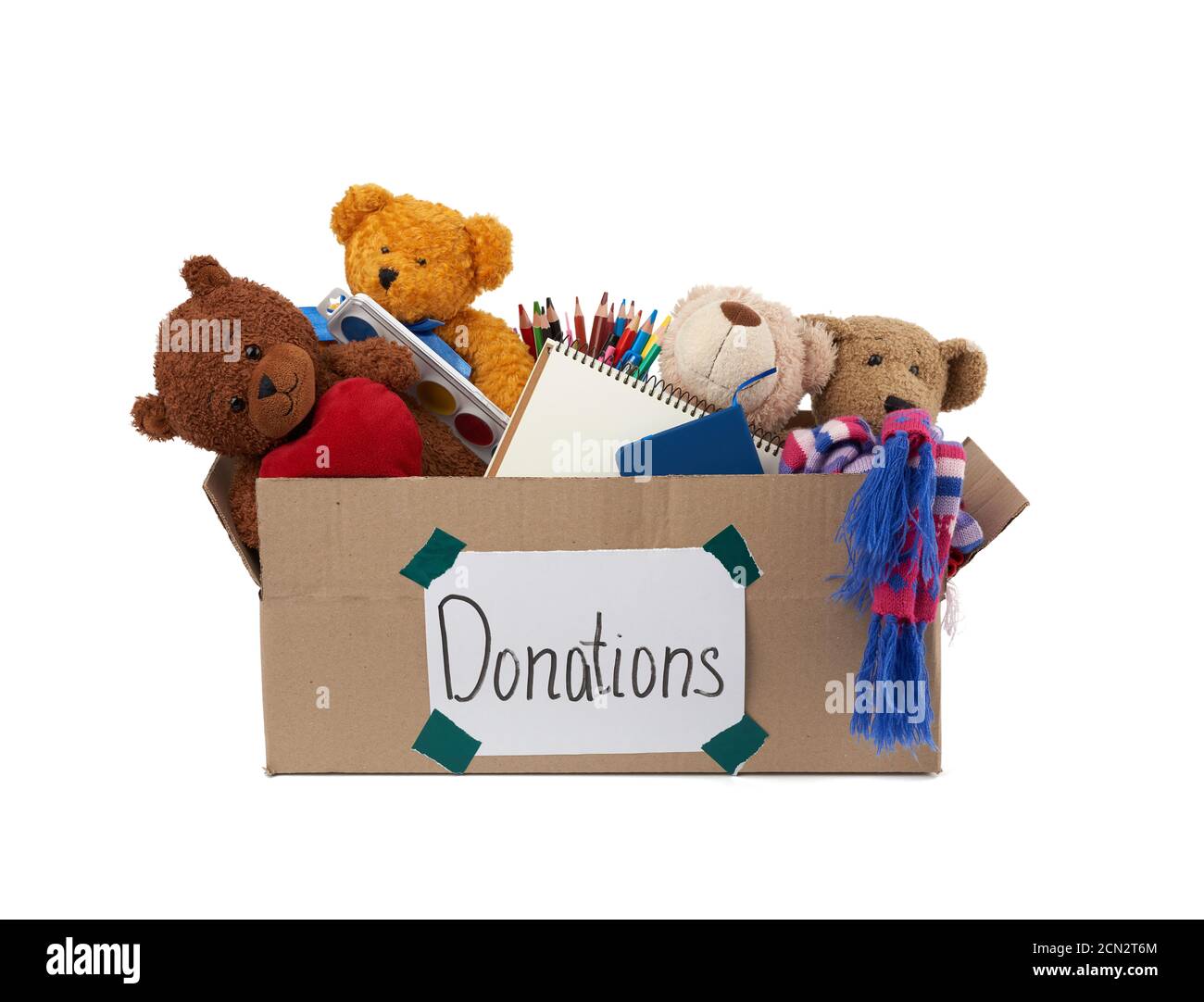 Braune Pappschachtel gefüllt mit weichem Spielzeug, Schulbedarf auf weißem Hintergrund, Konzept der Nächstenliebe Stockfoto