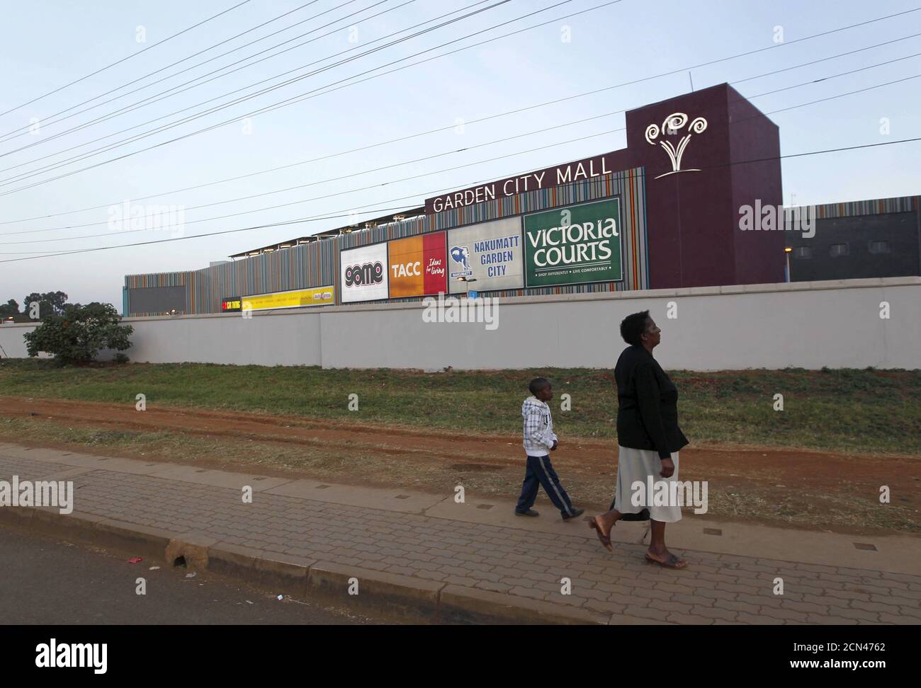 Eine Frau und ein Kind gehen vor der evakuierten Garden City Shopping Mall in Kenias Hauptstadt Nairobi, 8. September 2015. Ein großes, neues Einkaufszentrum in der kenianischen Hauptstadt Nairobi wurde am Dienstag evakuiert, als ein Mann mit einer mutmaßlichen selbstgemachten Bombe von Sicherheitskräften gestoppt wurde, sagten Polizei und Beamte des Einkaufszentrums. Die Polizei sagte, dass drei Männer im Zusammenhang mit dem Vorfall in der Garden City Mall, die im Mai als Teil eines 250-Millionen-Dollar-Projekts eröffnet wurde, verhaftet wurden. Kenianische Einkaufszentren sind seit 2013 in erhöhter Alarmbereitschaft, als vier bewaffnete Männer der somalischen militanten Gruppe al Shabaab das Einkaufszentrum Westgate Angriffen Stockfoto