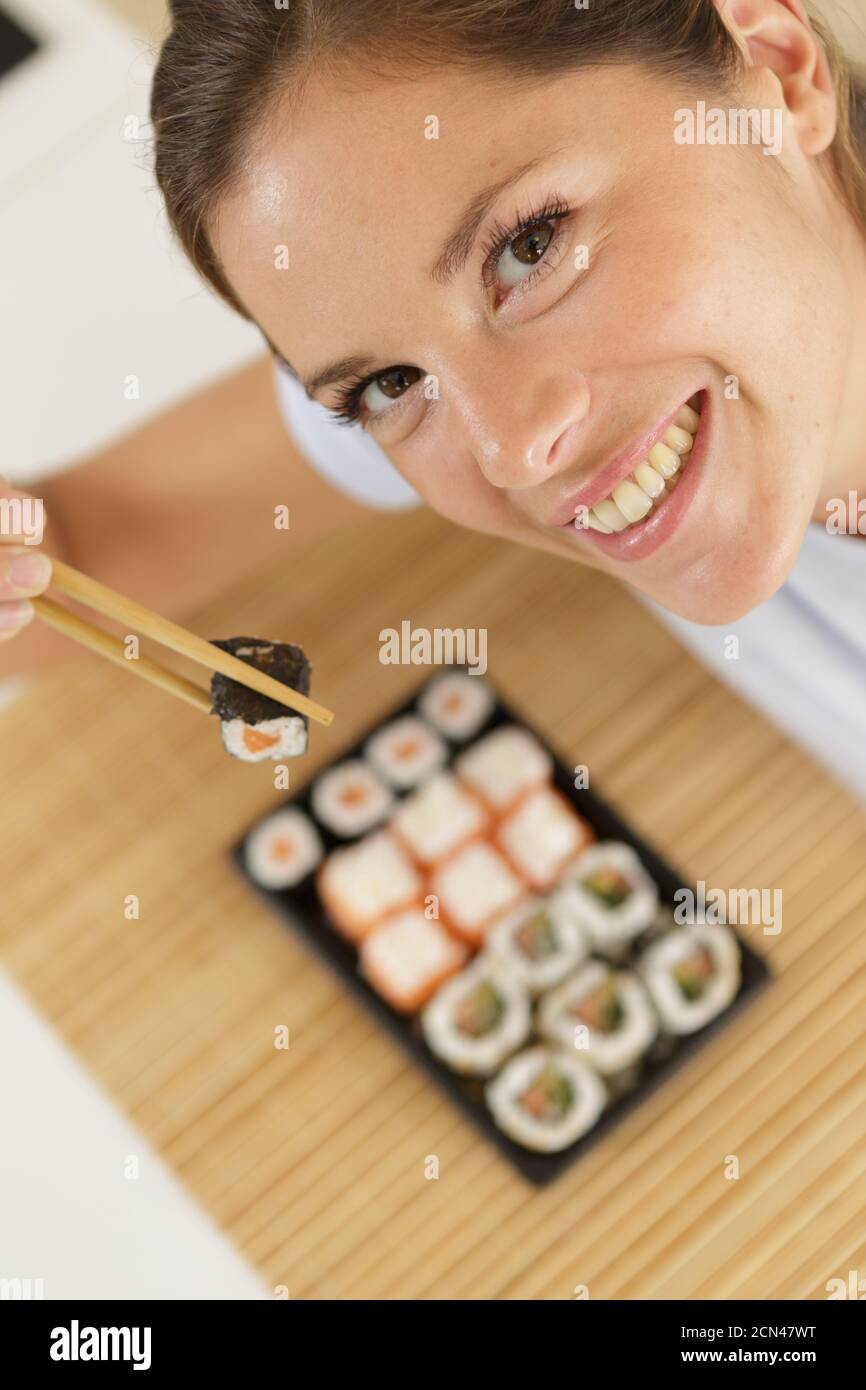 Schräg-Ansicht der Frau und hacken Sticks über Teller Sushi Stockfoto