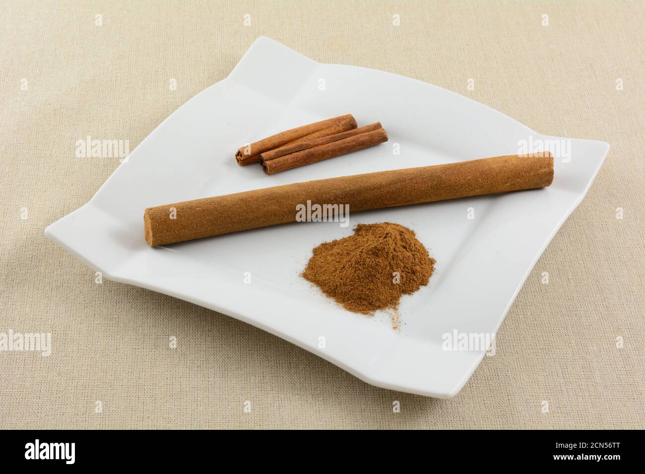 Niederländische Zimtstange Snack mit Zimtstange und Stapel Gemahlener Zimt auf weißem Snackteller auf hellbrauner Tischdecke Stockfoto
