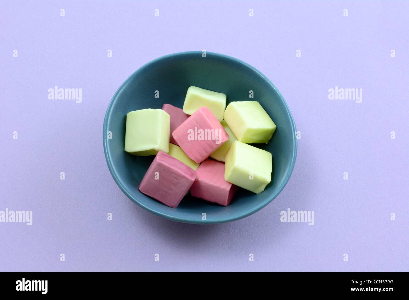 Fruchtsaft Kauen Bonbons in kleinen blauen Süßigkeitenschüssel auf Lavendel Hintergrund Stockfoto