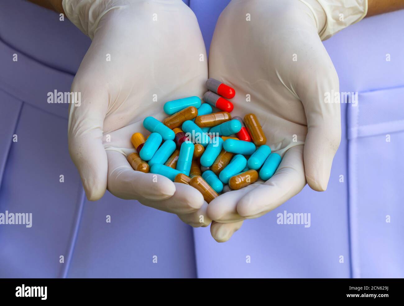 Bunte Pillen auf Einweg-Handschuh in der Hand des Arztes Stockfoto