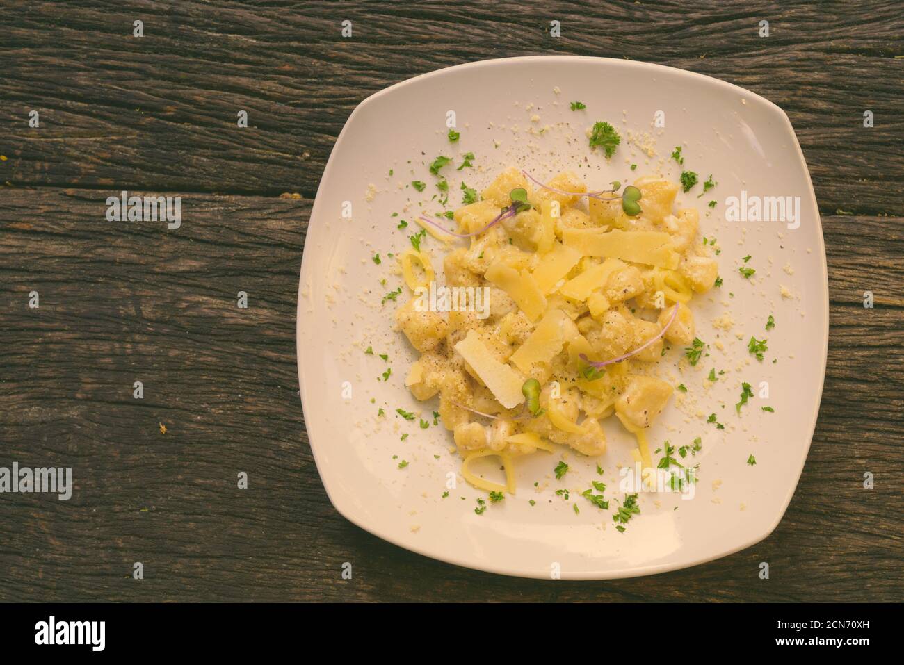 Gnocchi gemischt mit Käse und Sahne gegen Holztisch Stockfoto
