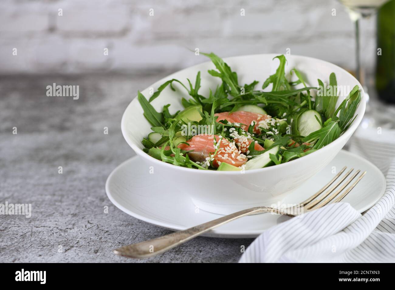 Gemüsesalat aus Rucola, Avocado und Gurkenstücken mit Zusatz von zartem gesalzenem Lachs, Stockfoto