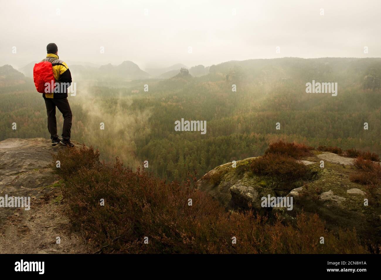 Tourist mit Rucksack macht Fotos mit Smartphone von regnerischen vally. Verträumt nebligen Tal unten Stockfoto