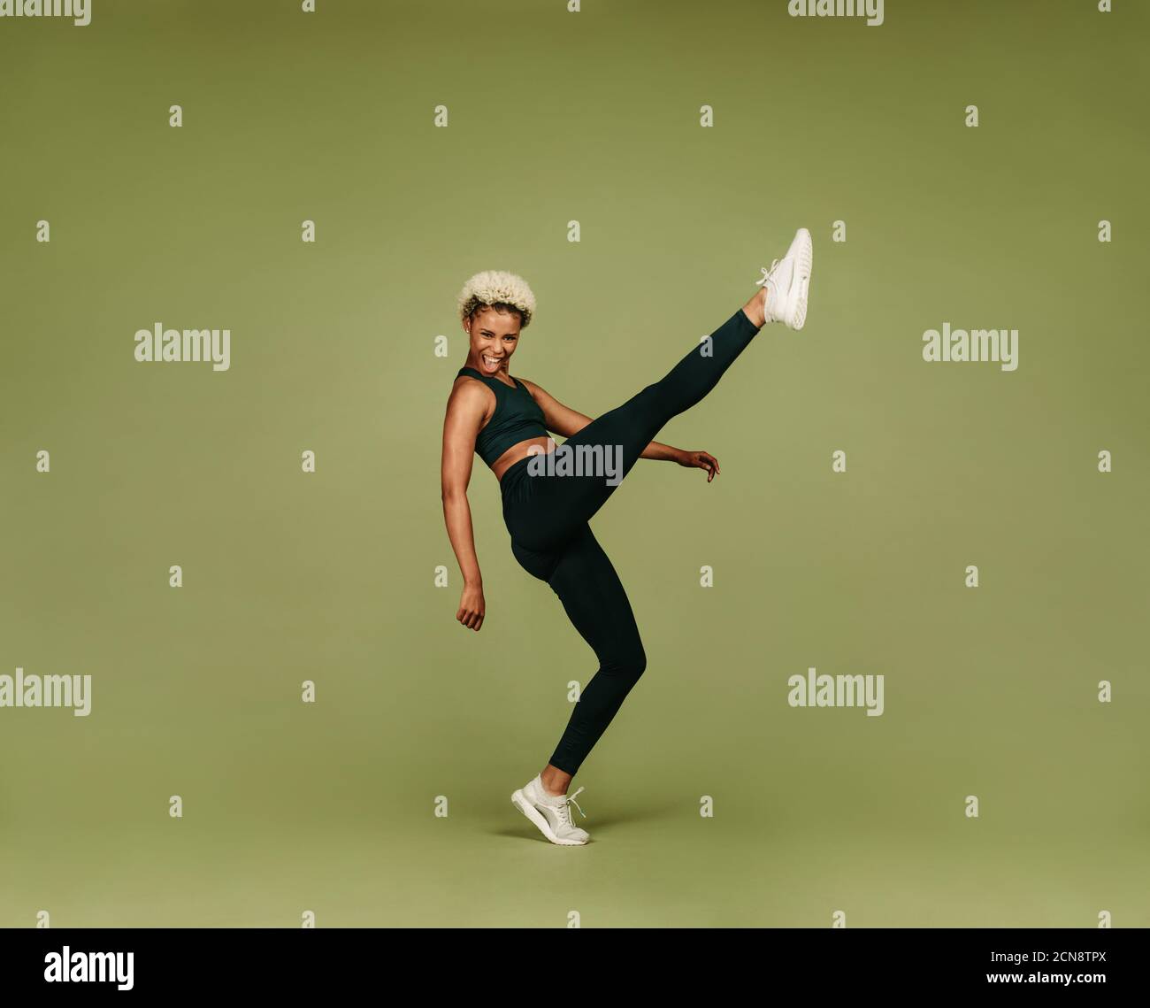 afroamerikanische Athletin macht Aufwärmübungen. Frau in Fitness tragen heben ihr Bein dabei Stretching-Übungen. Stockfoto