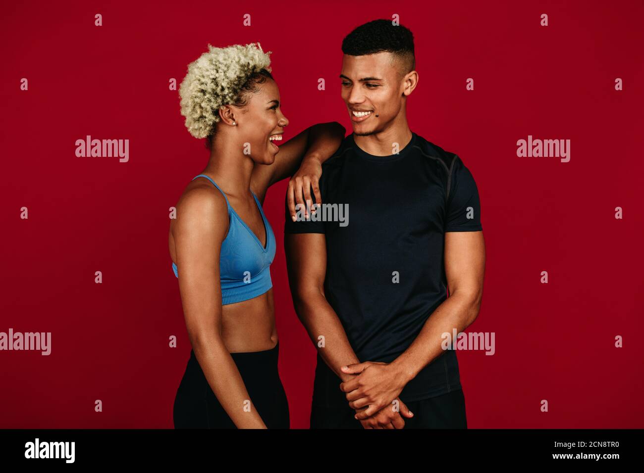 Fitnesspaar, das sich nach dem Training entspannt. Porträt eines afroamerikanischen Fitness-Paares, das lacht und miteinander redet. Stockfoto