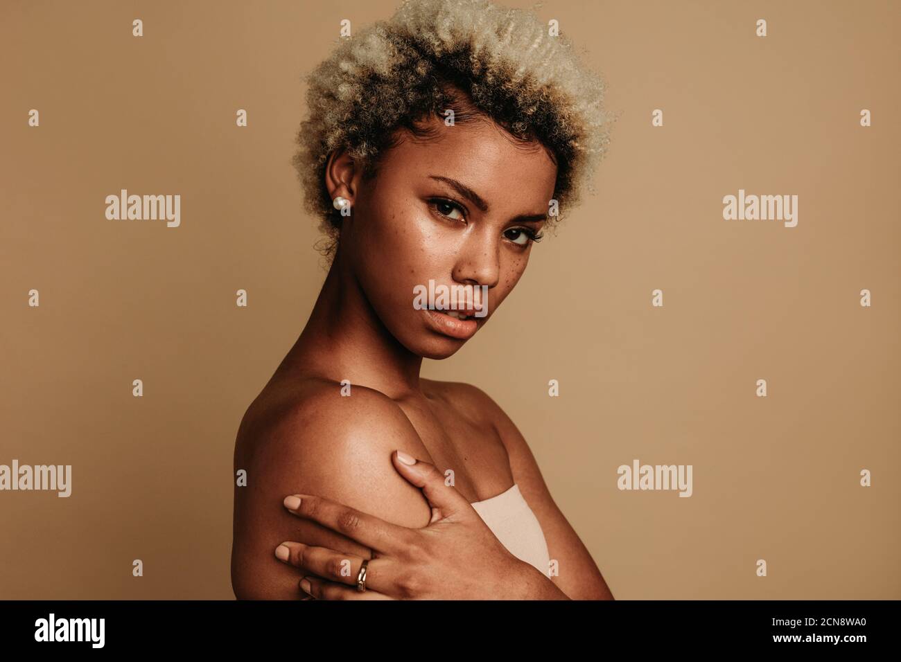 Seitenansicht Nahaufnahme einer afroamerikanischen Frau auf braunem Hintergrund. Porträt einer Frau mit lockigen braunen Haaren. Stockfoto