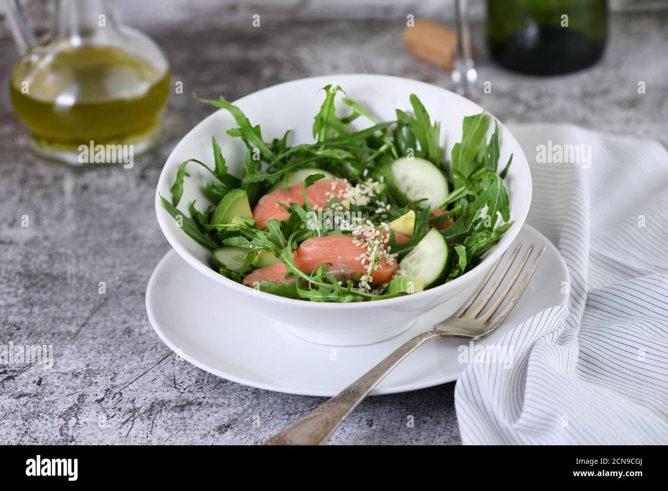 Gemüsesalat aus Rucola, Avocado und Gurkenstücken mit Zusatz von zartem gesalzenem Lachs, Stockfoto