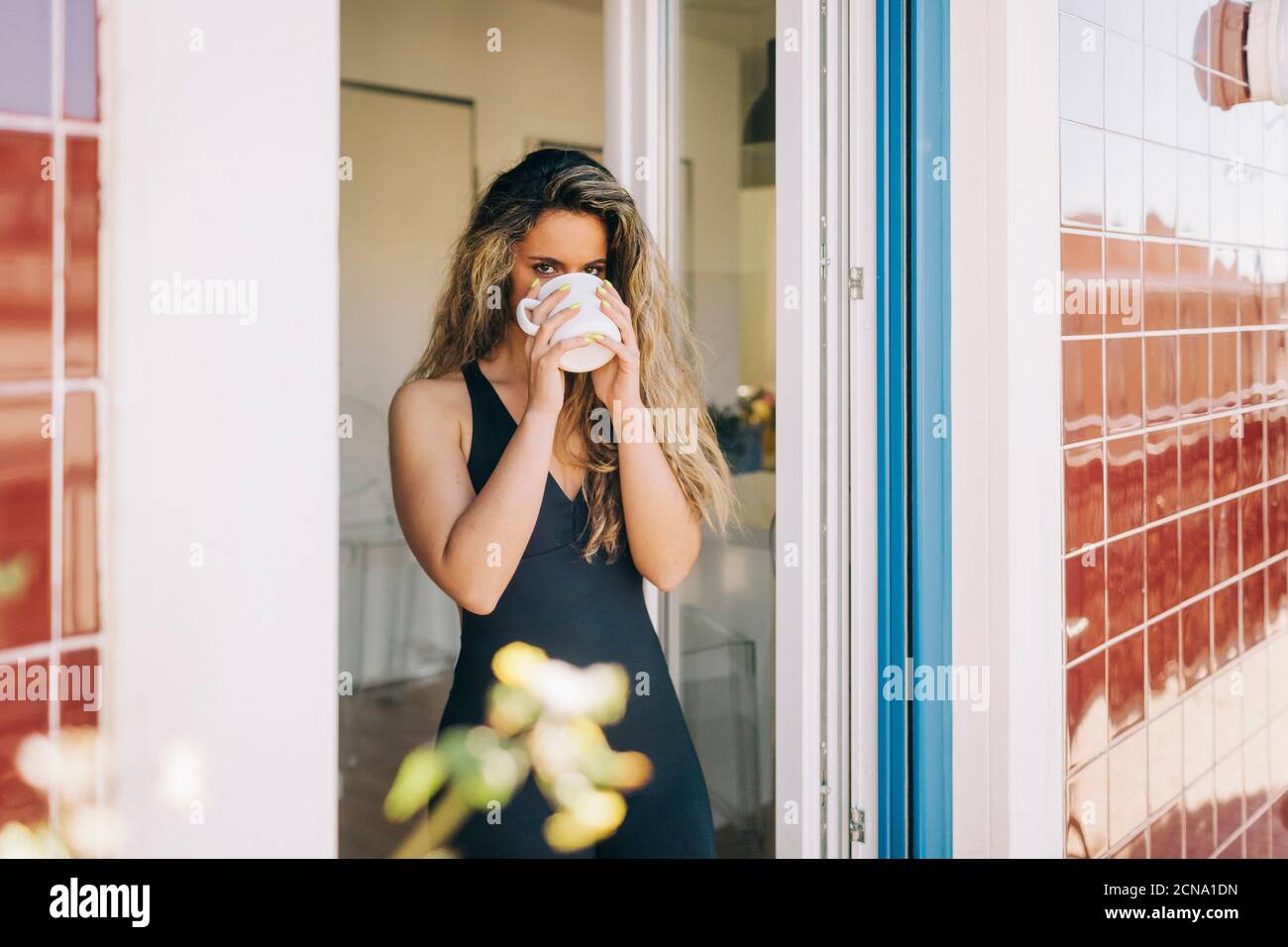 Portrait junge Frau trinkt Kaffee in Terrasse Tür Stockfoto