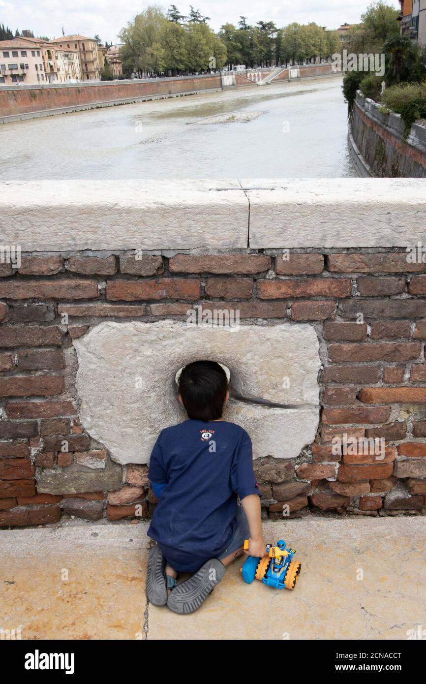 Kleiner Junge schaut durch ein Loch auf Ponte Pietra in Verona, Venetien, Italien, Europa. Stockfoto