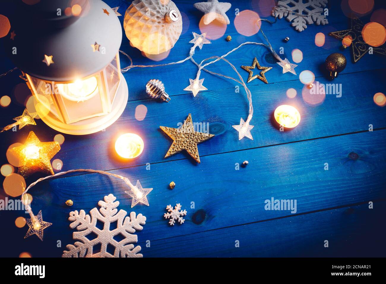 Brennende Laterne mit weihnachtsdekoration auf blauem Holzhintergrund. Stockfoto