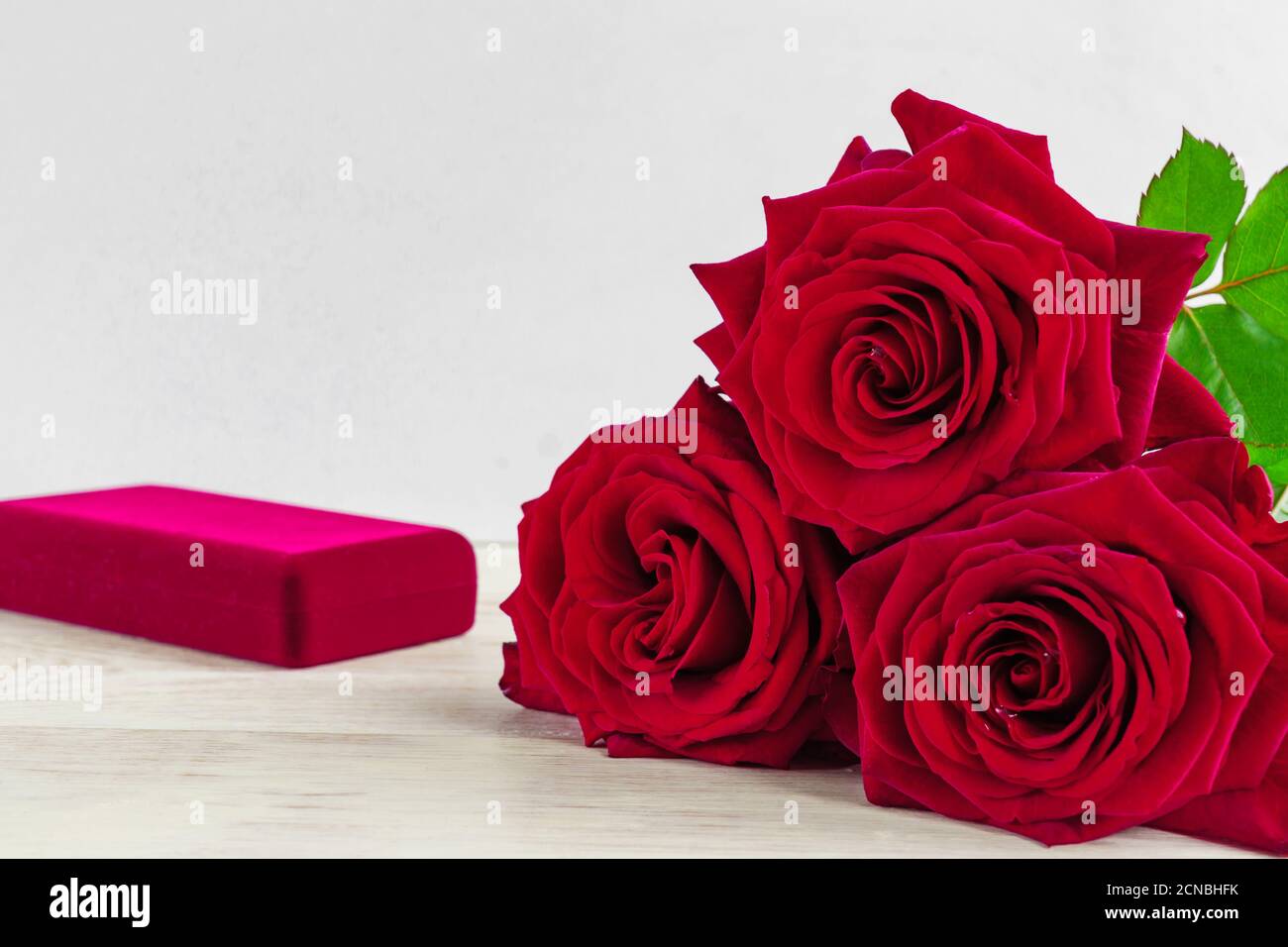 Schmuckschatulle und wunderschöne rote Rosen auf Holzhintergrund. Stockfoto