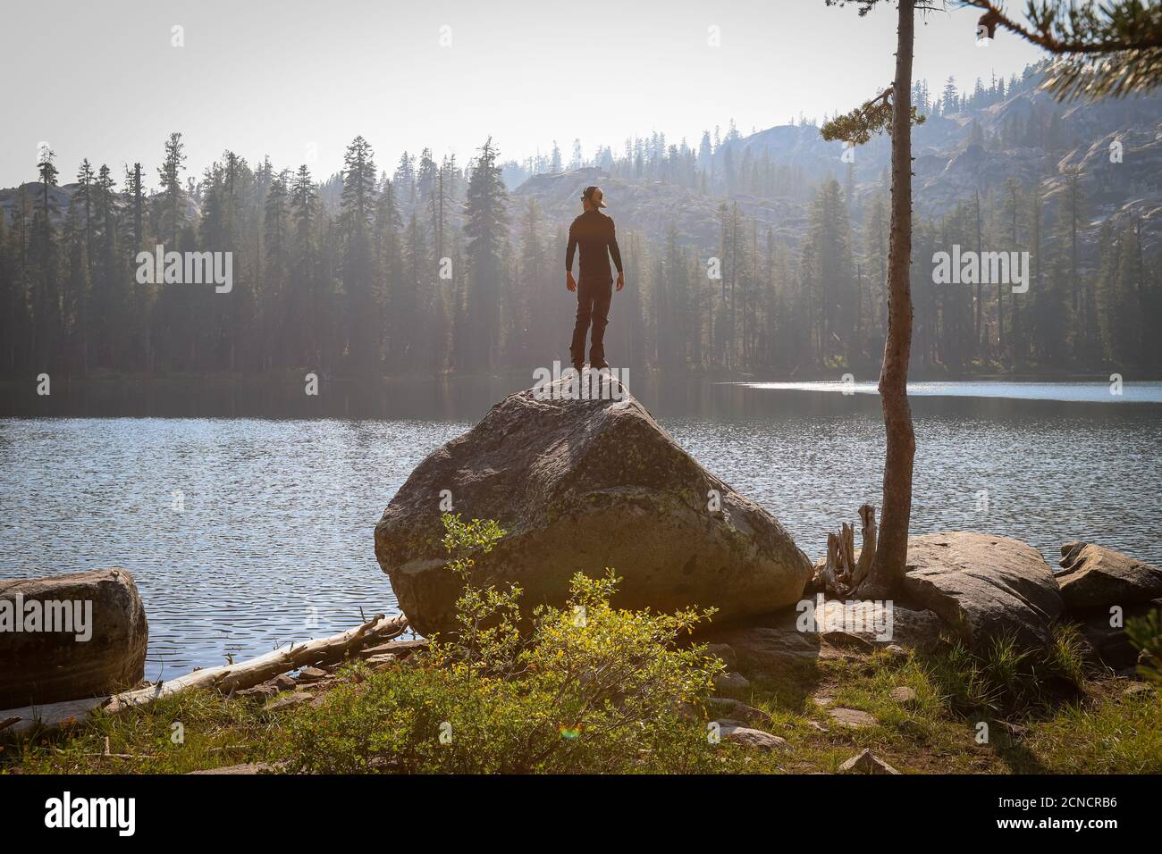 SODA SPRINGS, CALIFORNIA, USA - Sep 04, 2020: Ein männlicher Wanderer steht auf einem Granitfelsen mit Blick auf den Lower Lola Montez Lake nach einer Anhöhe Stockfoto