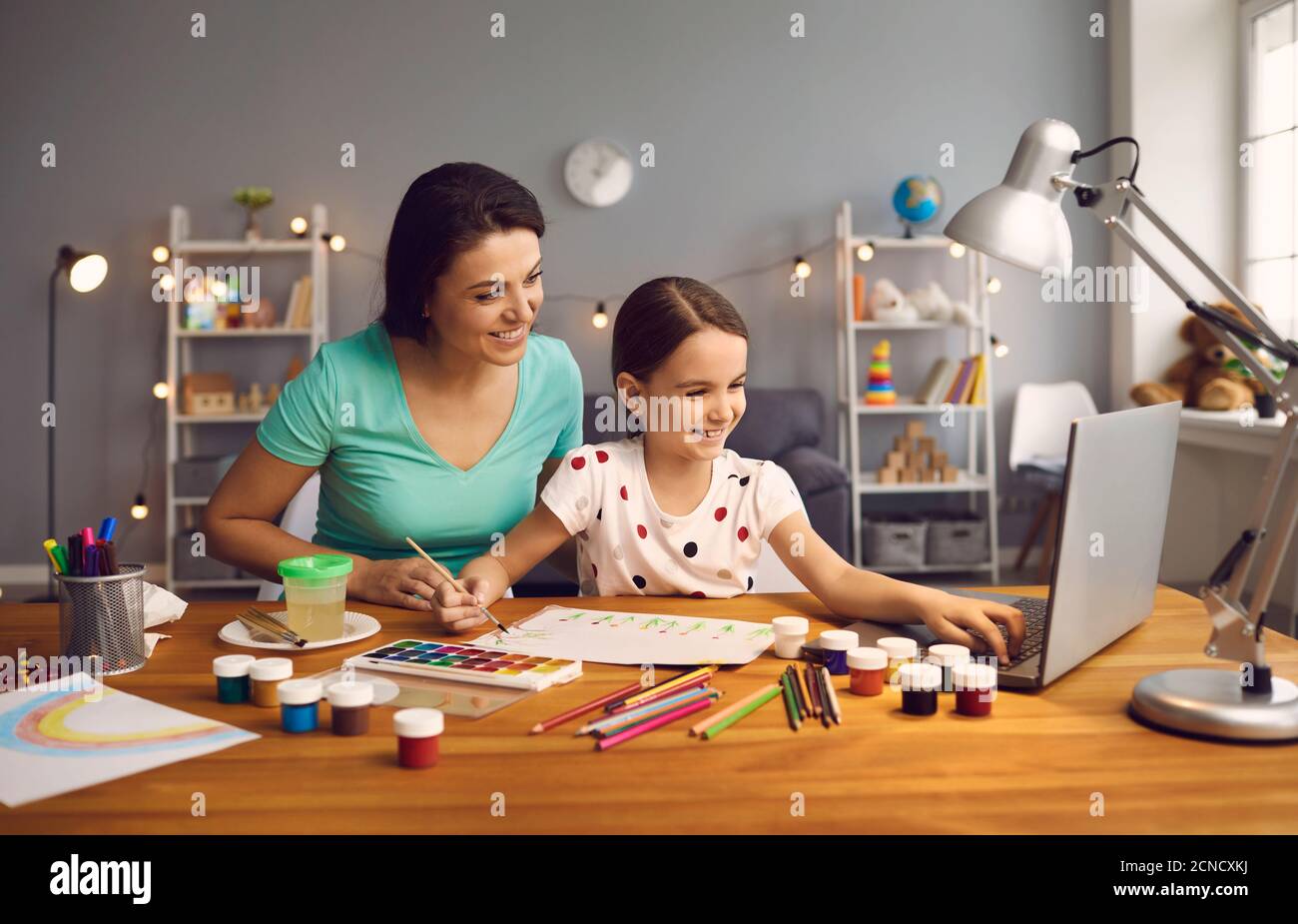 Online-Bildung von Kindern. Mutter und Tochter der Vorschule beobachten eine Video-Lektion Anruf Chat kreativen Kurs Kunst Zeichnung mit lapott zu Hause. Stockfoto