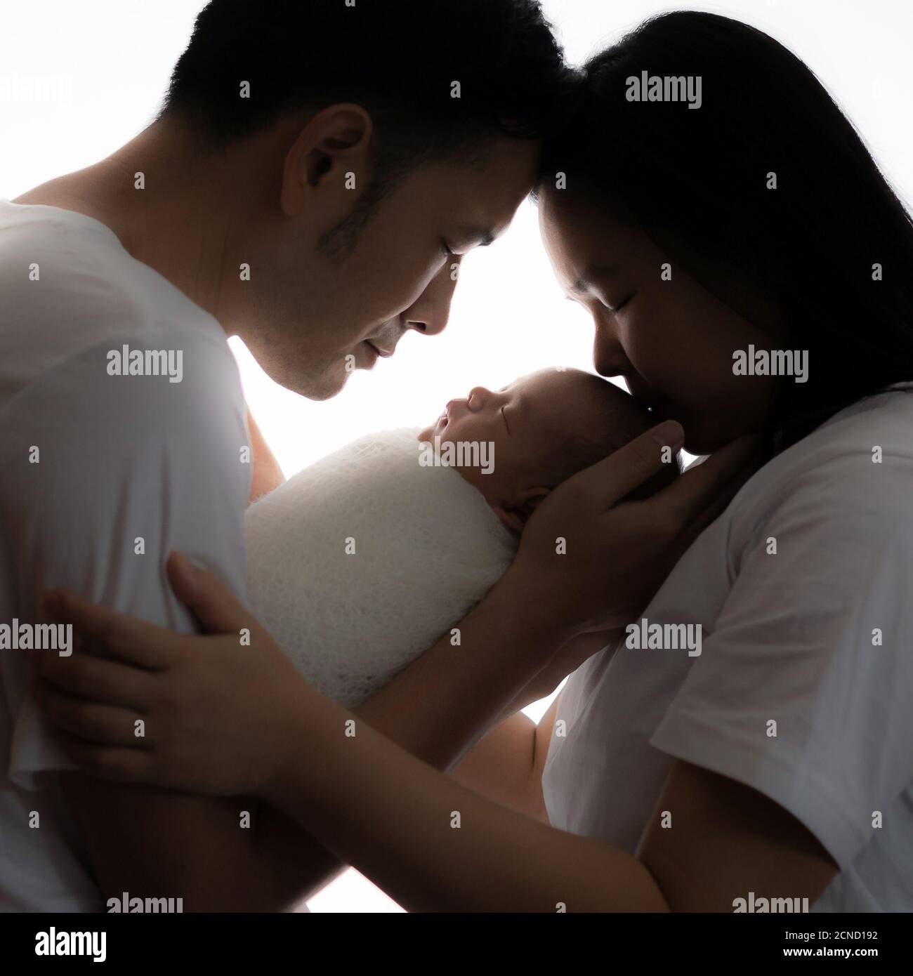 Glückliche asiatische Familie von Mutter Vater und Baby-Sohn im Studio Drehporträt umarmen zusammen lächelnd mit geschlossenen Augen. Elternschaft und Familie Stockfoto