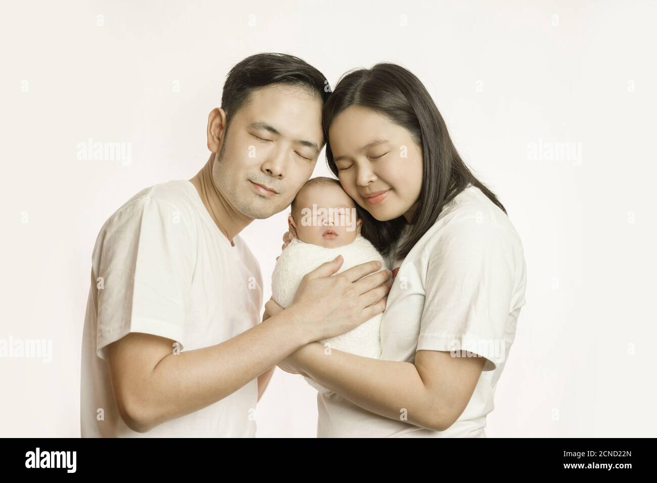 Glückliche asiatische Familie von Mutter Vater und Baby-Sohn im Studio Drehporträt umarmen zusammen lächelnd mit geschlossenen Augen. Elternschaft und Familie Stockfoto