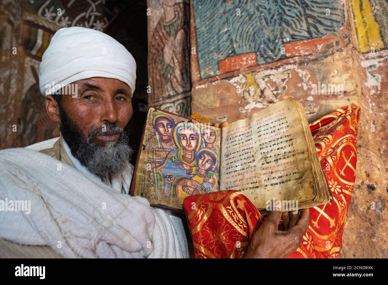 Orthodoxer Priester mit einer alten Bibel mit handgemalten Heiligen, Abuna Yemata Guh Kirche, Gheralta Berge, Tigray Region, Äthiopien, Afrika Stockfoto