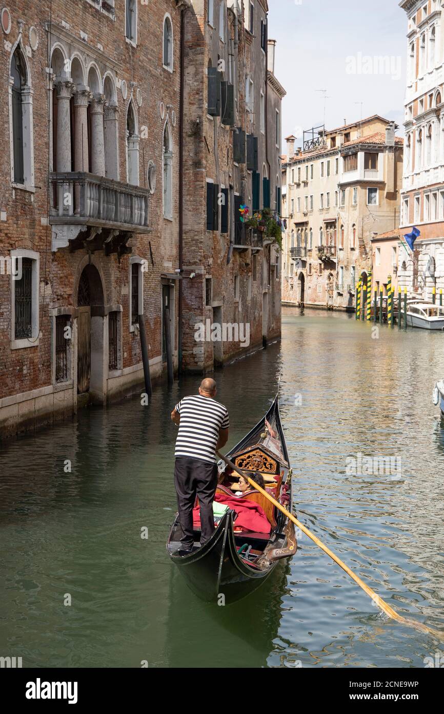 Gondoliere mit Touristen in Gondel auf Kanal in Venedig, Venetien, Italien, Europa. Stockfoto