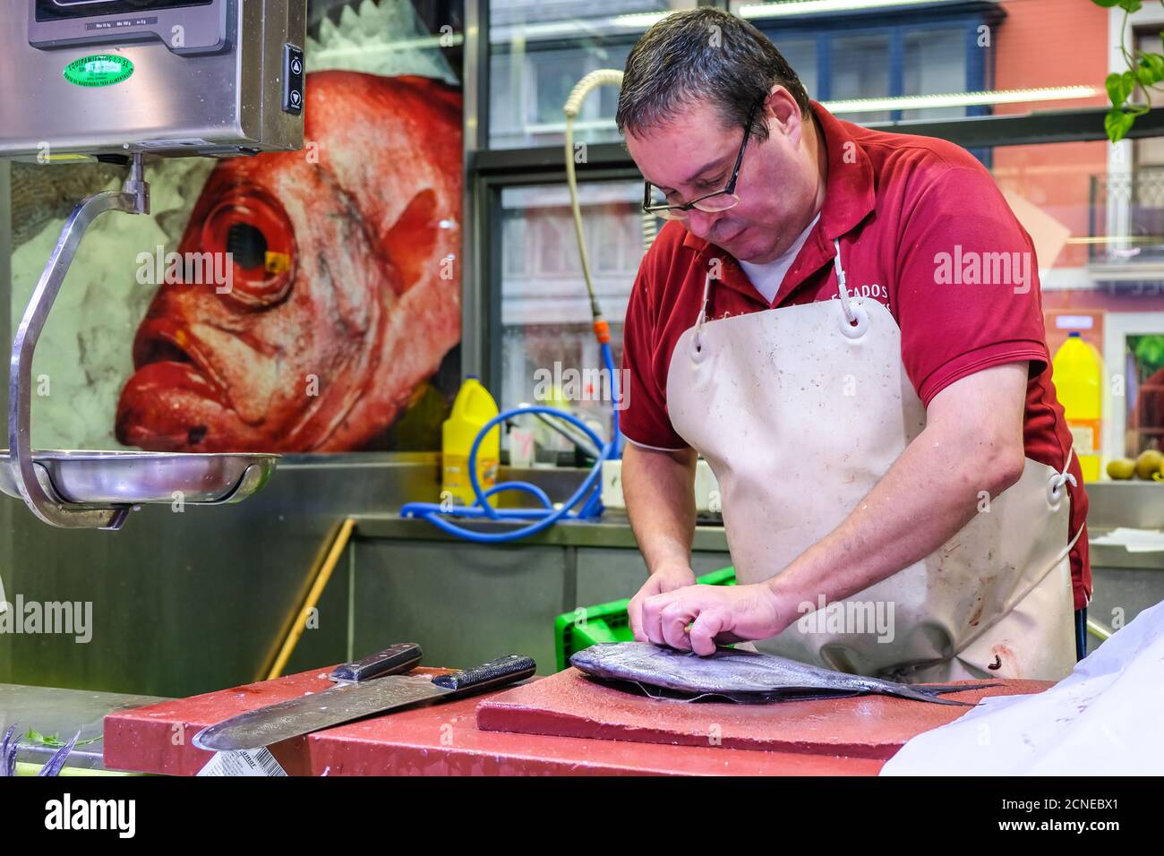Bilbao, Bizkaia, Spanien - 5. Oktober 2017. Ein männlicher Verkäufer schneidet Fisch mit einem Messer auf dem alten Ribera Lebensmittelmarkt mit lokalen Produkten Stockfoto