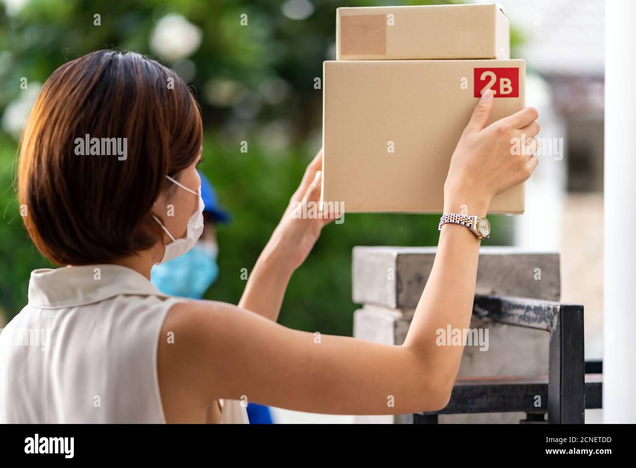 Rückansicht asiatische Kundin Frau nehmen Paket von kontaktloser Lieferung. Stockfoto