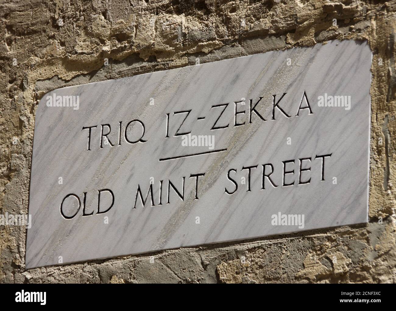 Geschnitztes Straßenschild für Old Mint Street, Triq Iz-Zekka an einer Wand in Valletta, Malta. Stockfoto