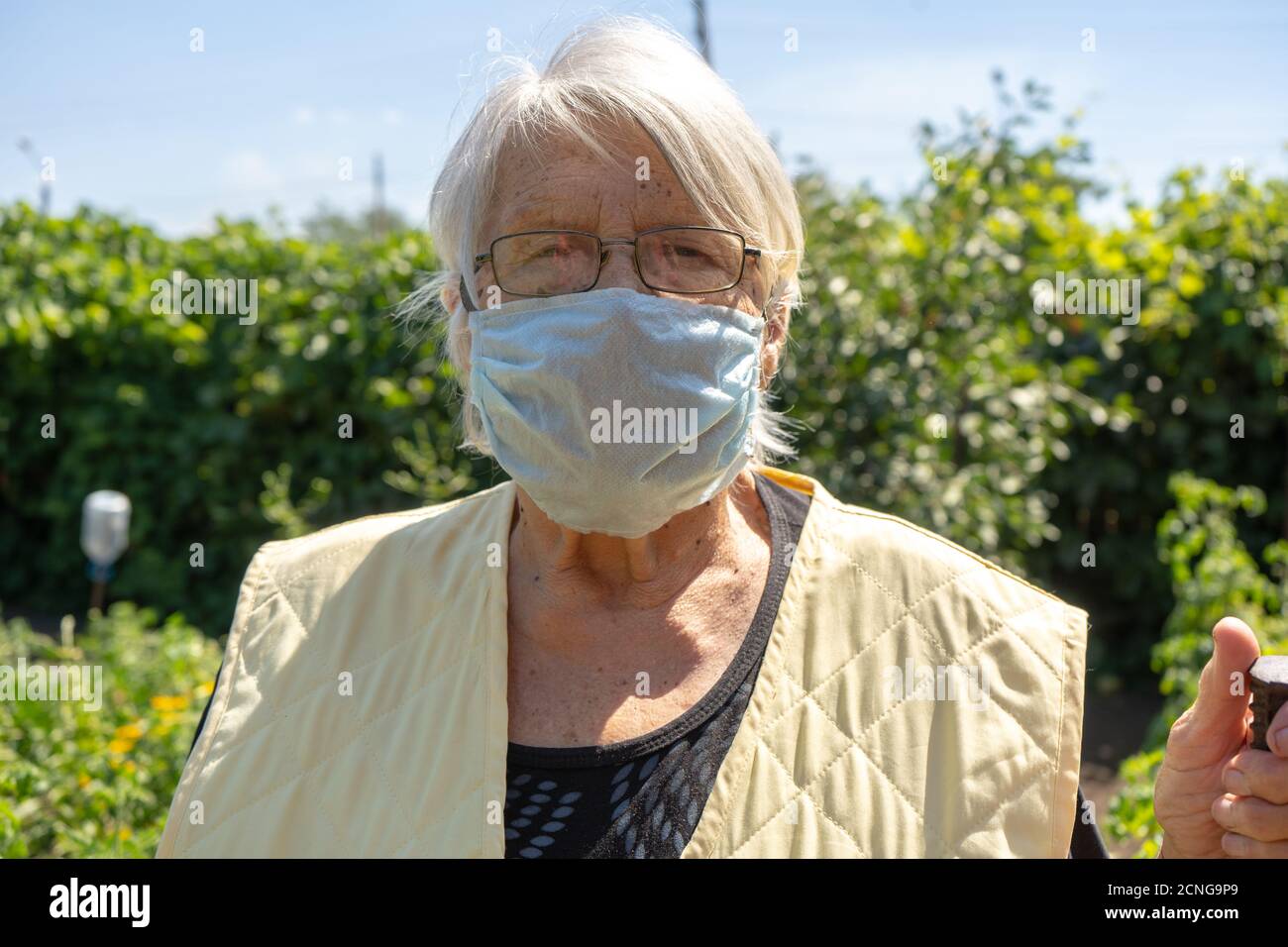 Alte Dame mit grauen Haaren tragen Schutzmaske, ältere Frau zu Hause in Quarantäne, Selbstisolation Stockfoto
