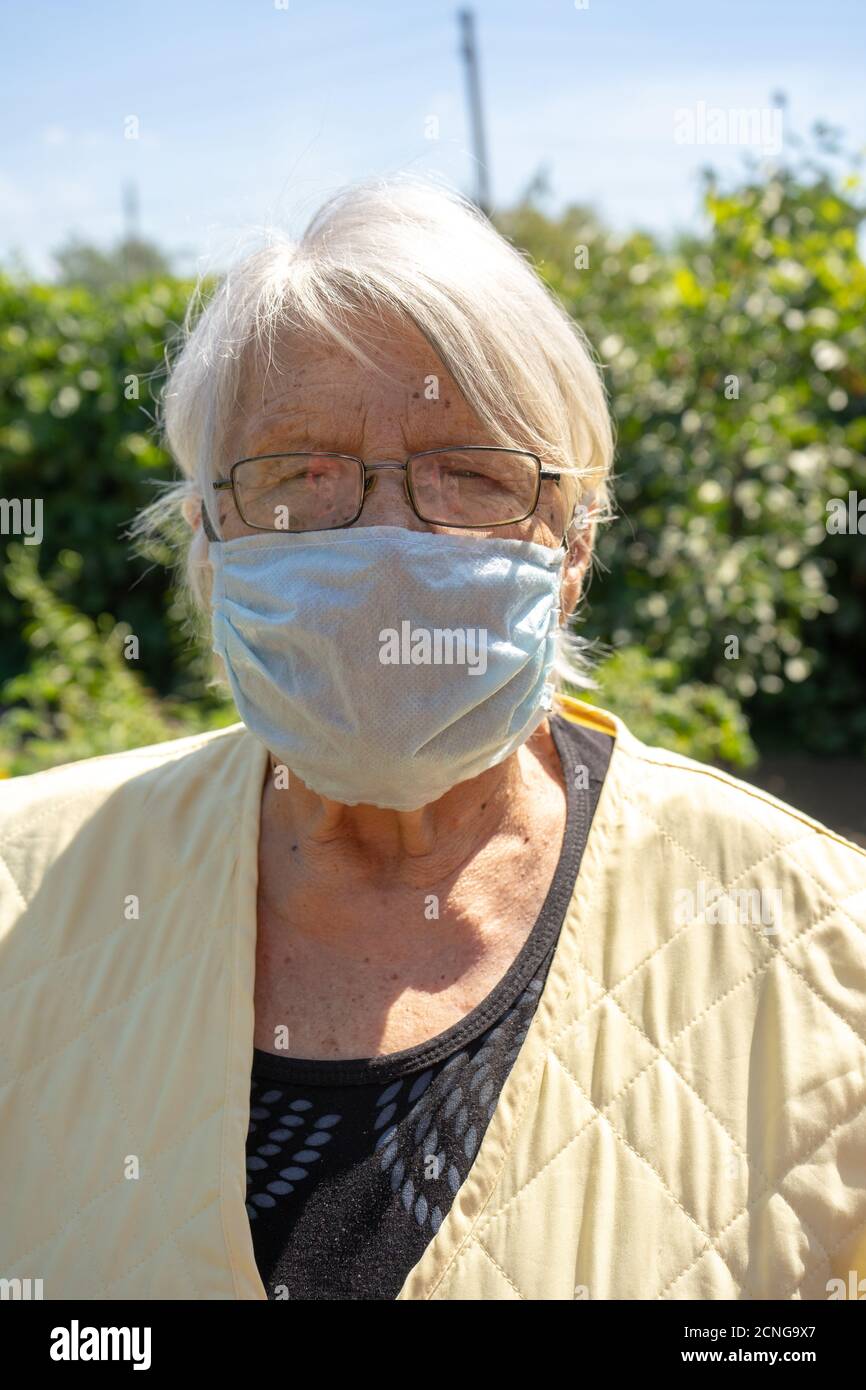 Alte Dame mit grauen Haaren tragen Schutzmaske, ältere Frau zu Hause in Quarantäne, Selbstisolation Stockfoto
