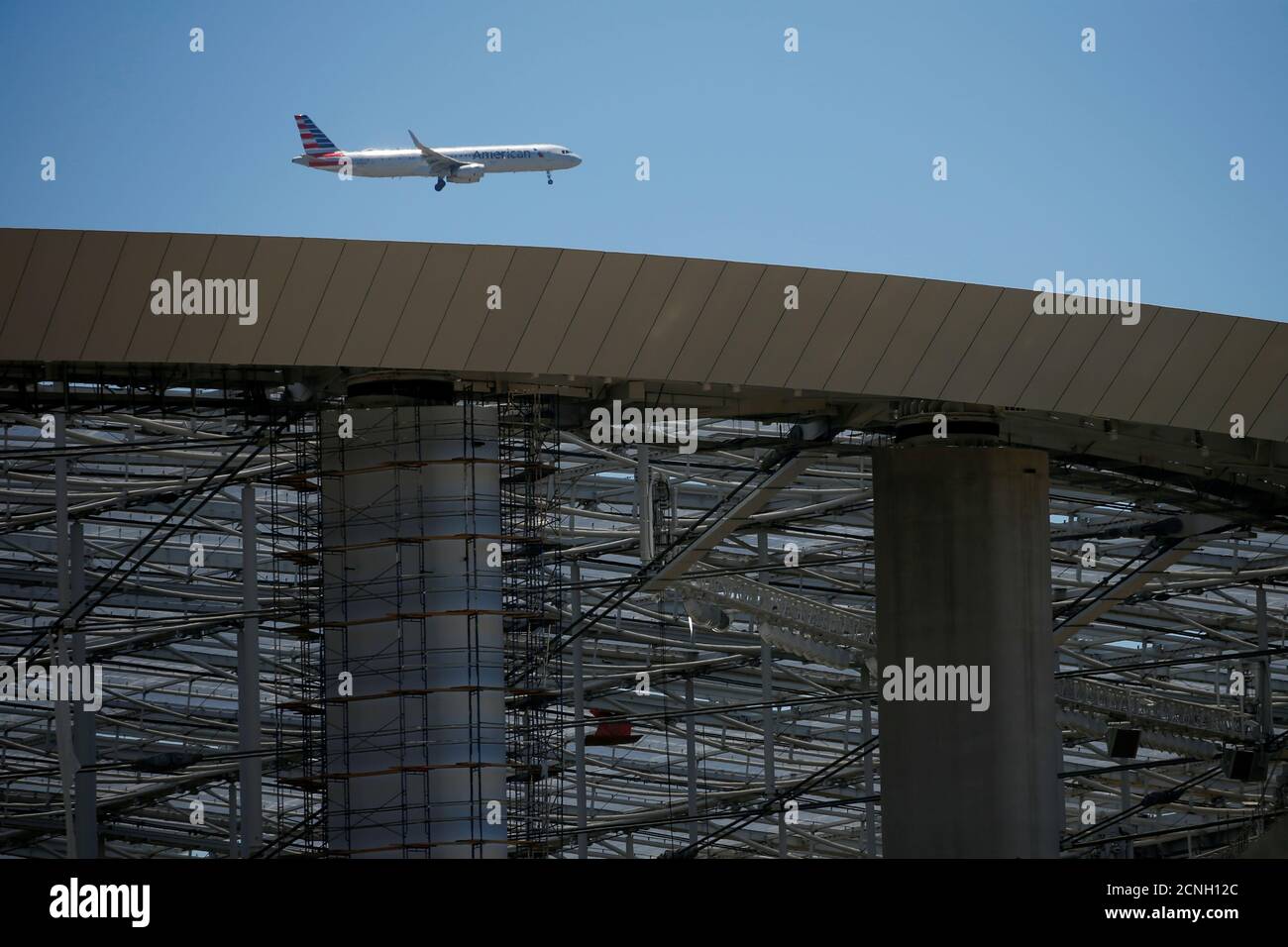 Ein Passagierflugzeug von American Airlines nähert sich der Landung am LAX, während es über das SoFi Stadium fliegt, das neue Zuhause der Los Angeles Rams der NFL, das derzeit in Inglewood, Kalifornien, USA, gebaut wird, 11. Juni 2020. REUTERS/Mike Blake Stockfoto