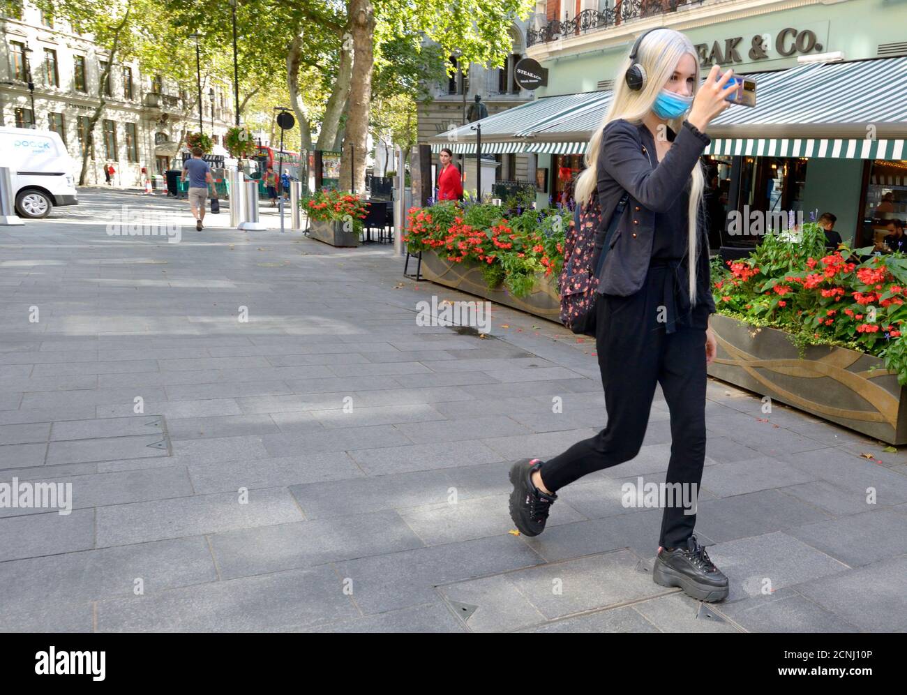 London, England, Großbritannien. Junge Frau mit langen Haaren, die sich auf ihrem Handy, Irving Street, filmte Stockfoto