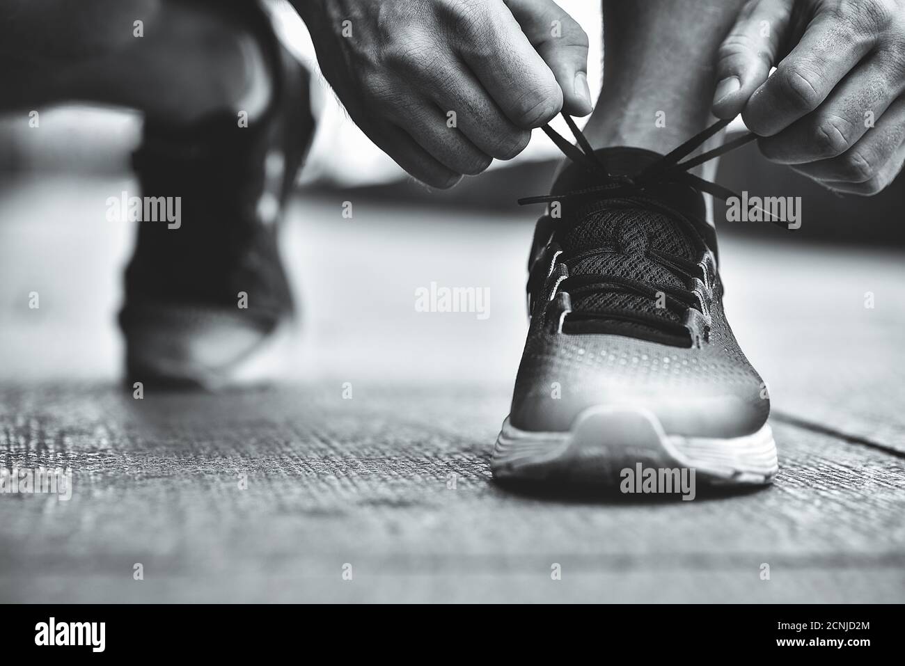 Nahaufnahme von Sportlern, die Sneakers binden. Nicht erkennbarer Mann hält Schnürschuh im Freien. Sportschuhe Konzept. Farbversion Stockfoto