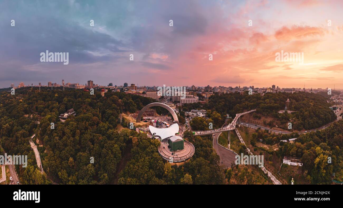 Panoramablick auf Kiew vom Himmel. Sonnenuntergang über Sommer Kiew mit Bogen der Freundschaft der Völker. Gefilmt auf Drohne. Luftaufnahme Stockfoto