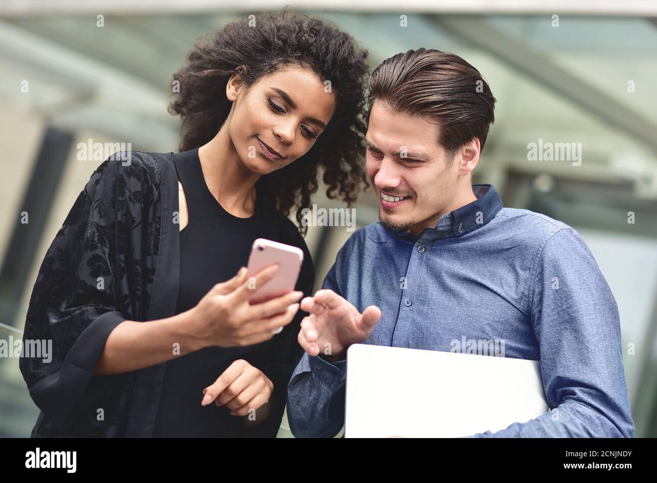 Geschäftstreffen. Mann und Frau diskutieren über die Arbeit und schauen auf den Smartphone-Bildschirm. Gemeinsam im Freien arbeiten. Stockfoto