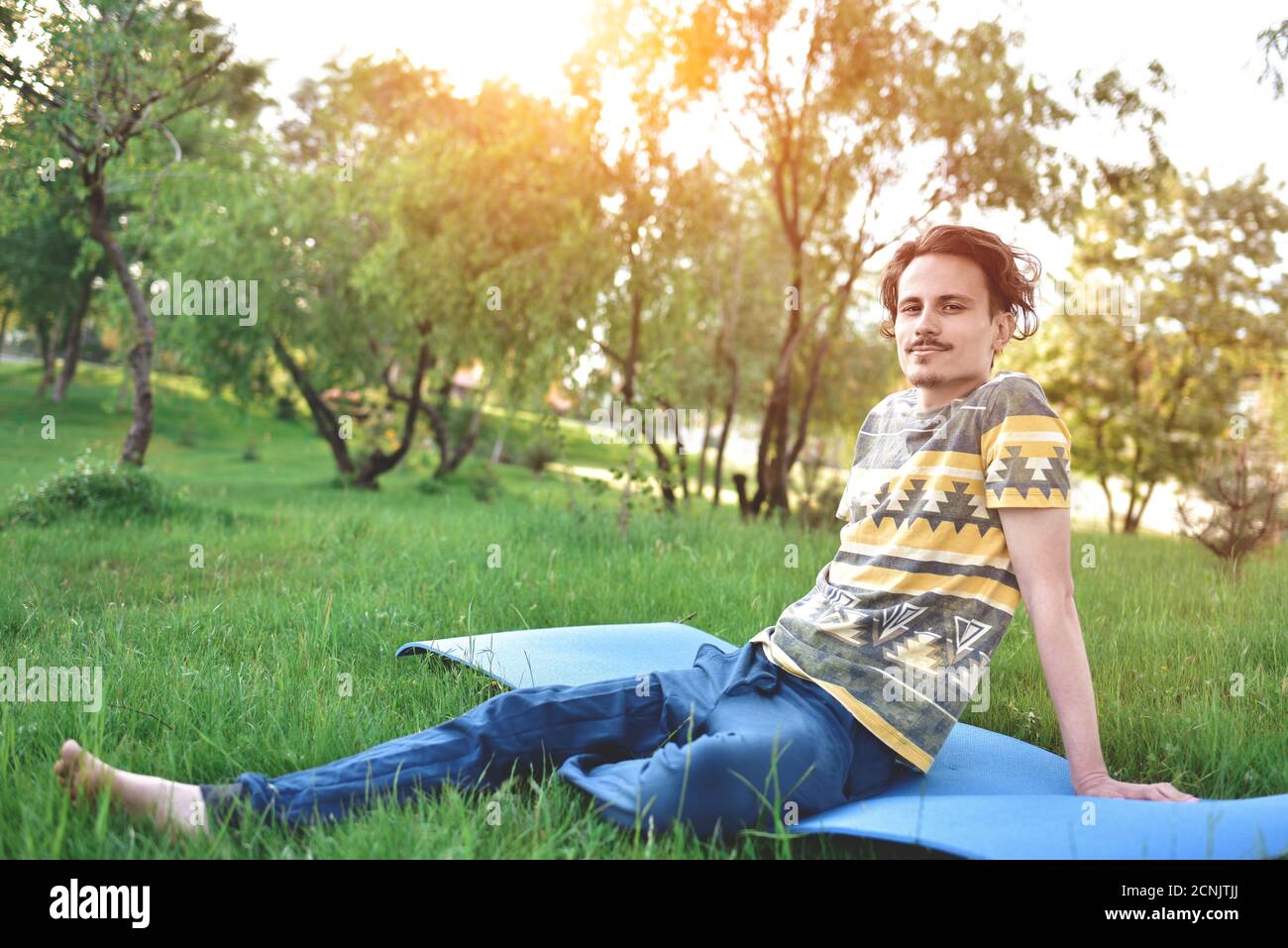 Schöner stilvoller Kerl genießt die Natur und träumt von etwas im Park sitzen. Friedlicher Blick Stockfoto