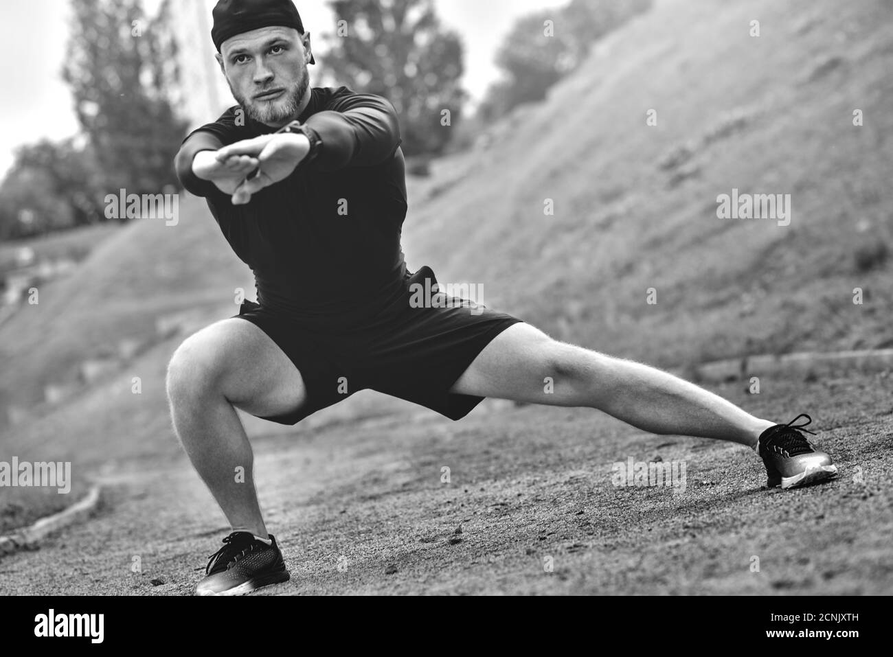 Junge kaukasische männliche Jogger mit Fitness-Tracker am Arm aufgewärmt vor dem Joggen. Stockfoto