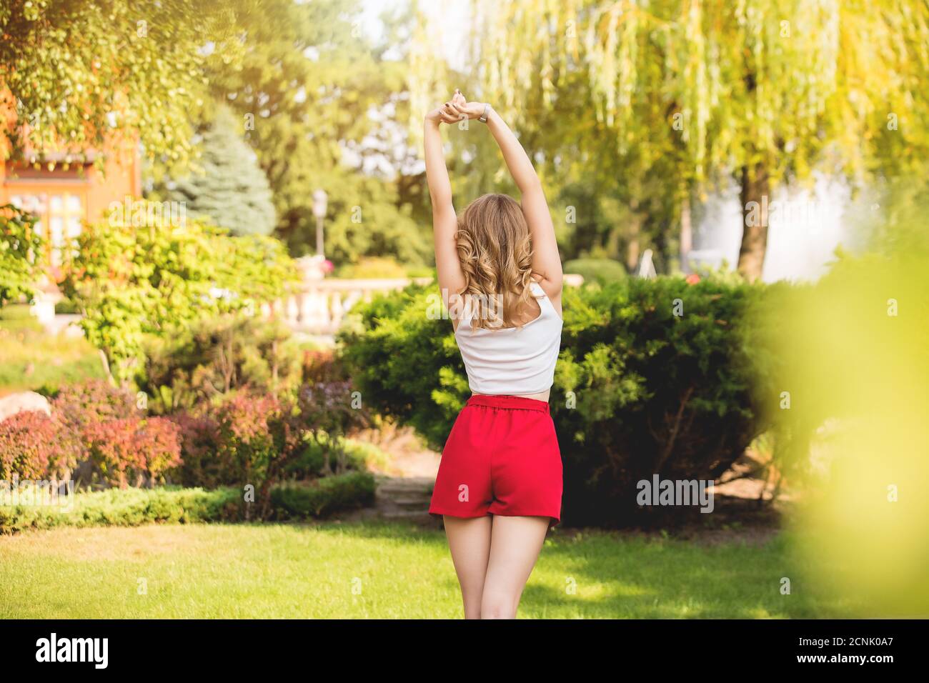Eine junge Frau in roten Shorts steht mit ihr Zurück auf einem Naturhintergrund Stockfoto
