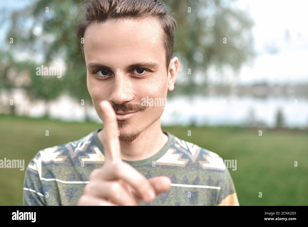 Ein Kerl mit einem schlauen Ausdruck auf seinem Gesicht, zeigt eine Fingerbewegung, sagt, versuchen Sie nicht, mich zu täuschen Stockfoto