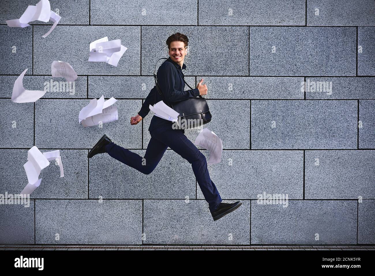 Lächelnder Geschäftsmann läuft schnell mit Aktentasche in der Stadt Stockfoto