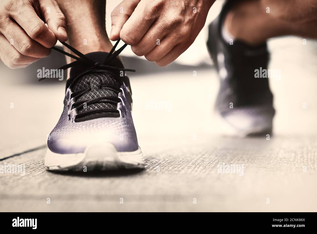 Nahaufnahme von Sportlern, die Sneakers binden. Nicht erkennbarer Mann hält Schnürschuh im Freien. Sportschuhe Konzept. Farbversion Stockfoto