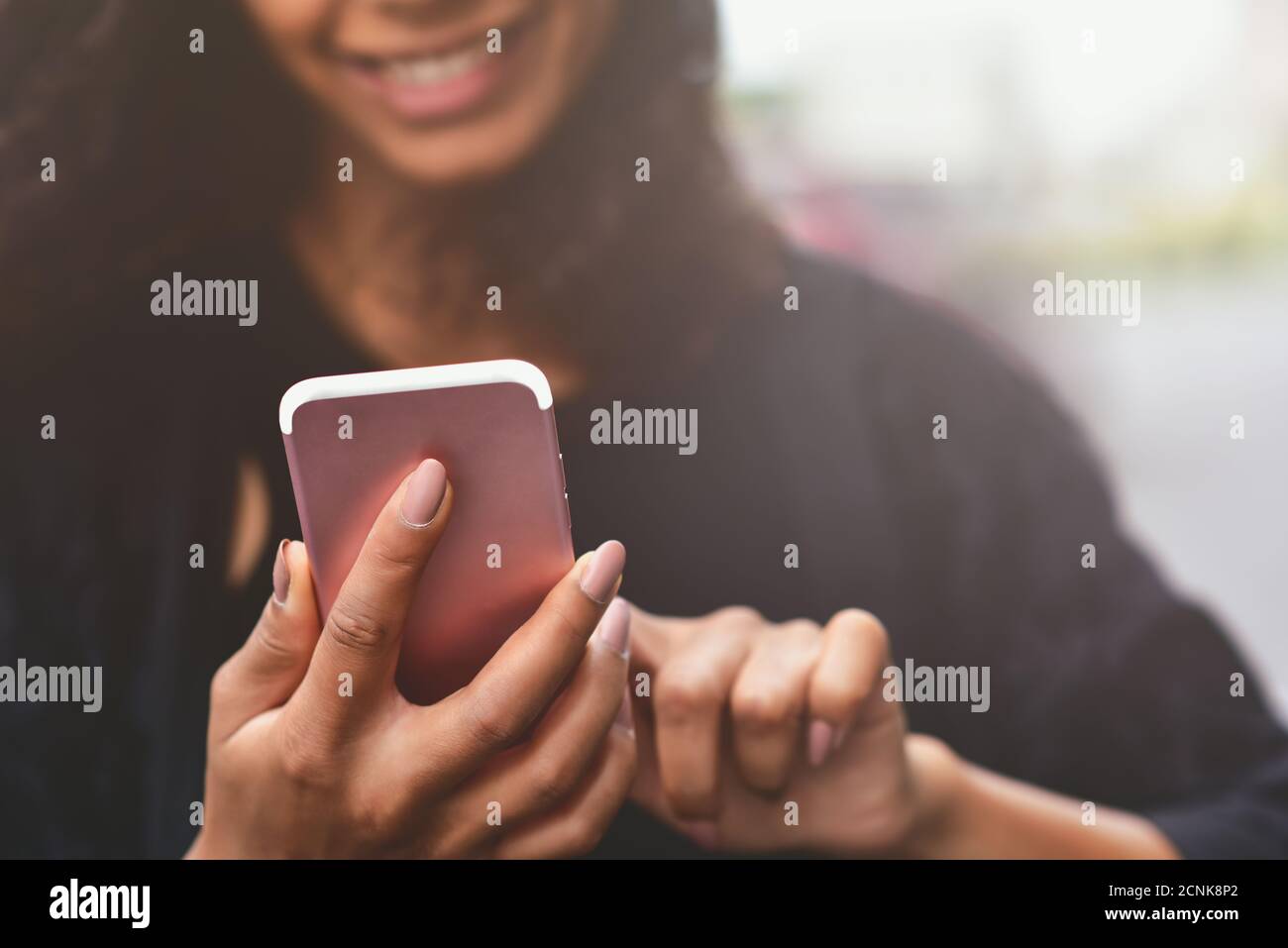 Nahaufnahme Bild einer schönen gemischten Rasse Frau halten, mit und Blick auf Smartphone. Stockfoto
